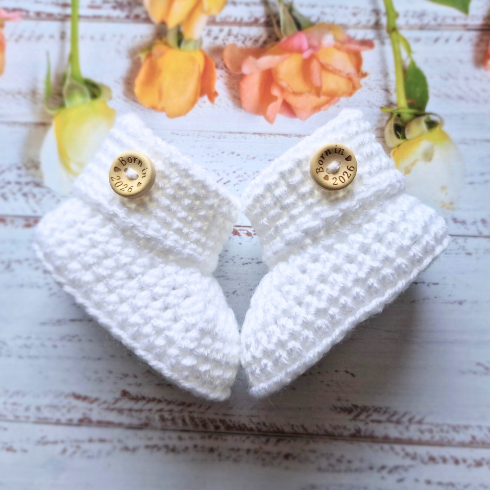 Handmade ‘Born in 2026’ Crochet Baby Booties – Handmade Newborn Gift or Pregnancy Reveal – Baby Booties crafted in soft acrylic yarn and available in multiple colours by Twisted by the Sea.