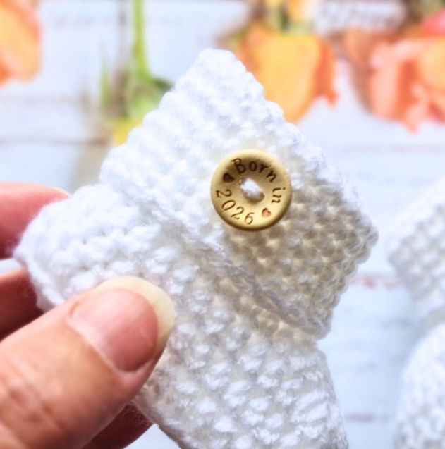 Handmade ‘Born in 2026’ Crochet Baby Booties – Handmade Newborn Gift or Pregnancy Reveal – Baby Booties crafted in soft acrylic yarn and available in multiple colours by Twisted by the Sea.
