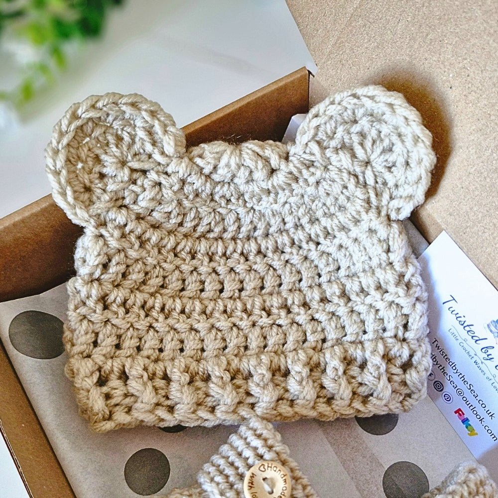 Beige crochet baby hat with ears on a box