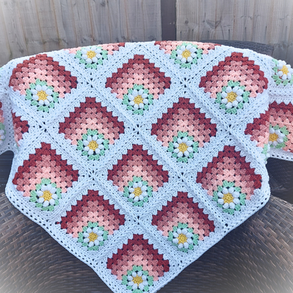 Crocheted blanket with a floral pattern on a wooden surface