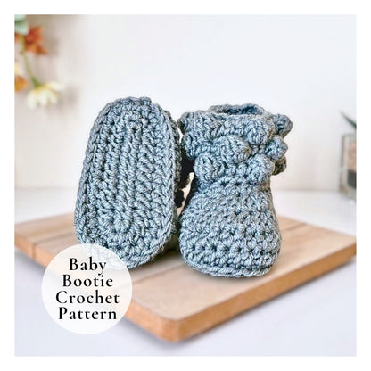 Pair of blue crochet baby booties on a wooden board with 'Baby Bootie Crochet Pattern' text.