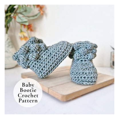 Pair of blue crochet baby booties on a wooden board with a blurred background