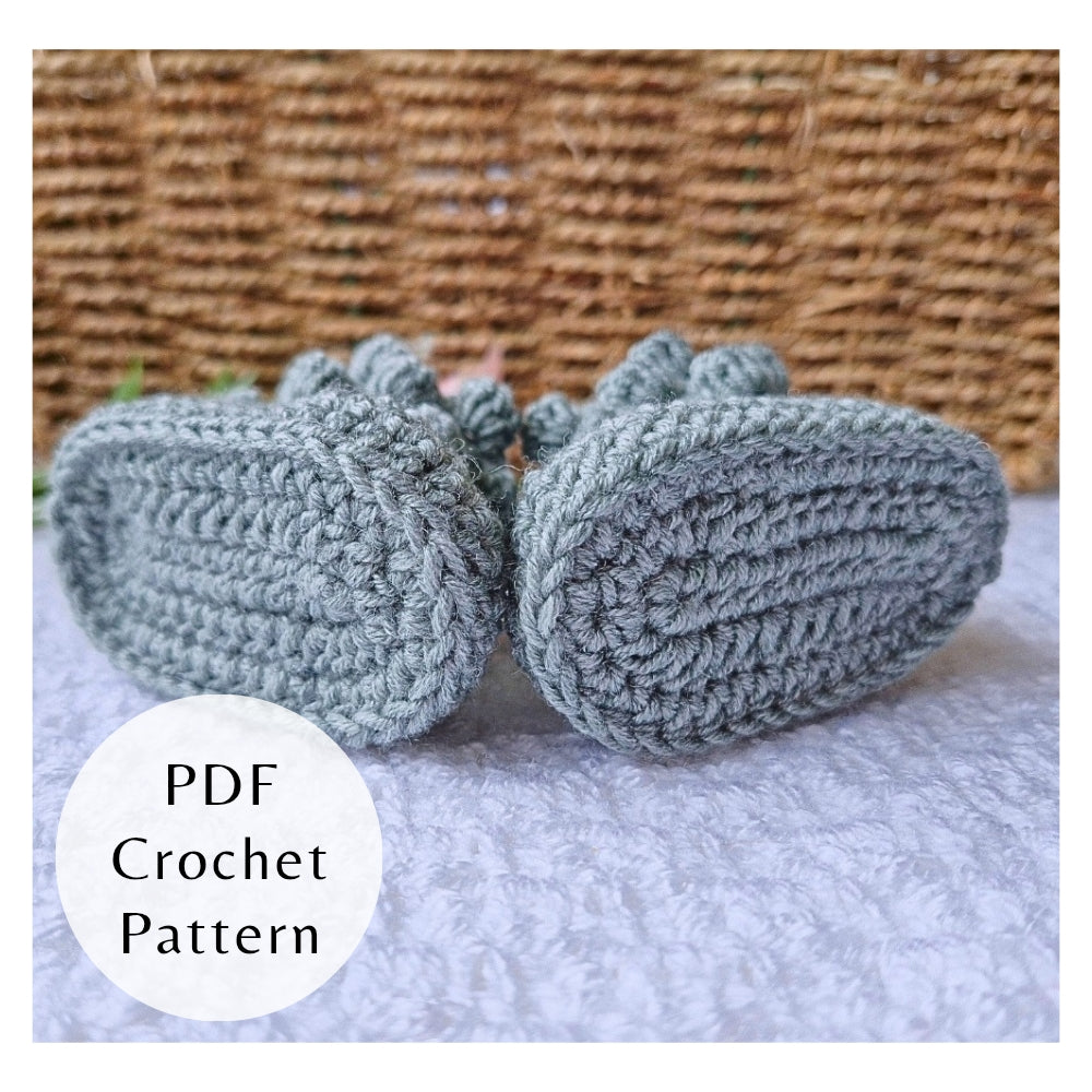 Pair of crocheted baby booties on a textured surface, PDF Crochet Pattern by Twisted by the Sea 