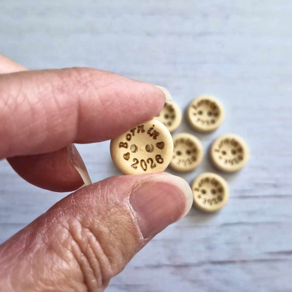 Handmade Born In 2026 Wooden Buttons – 15mm Natural Craft Buttons – Pack of 10, for Sewing, Knitting, Crochet – Buttons crafted in soft acrylic yarn and available in multiple colours by Twisted by the Sea.