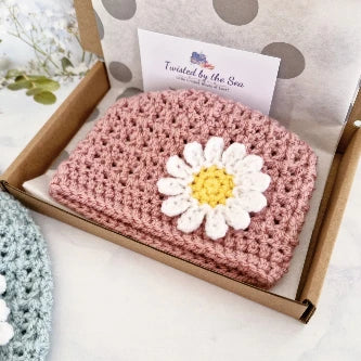 Boxed pale rose crochet baby hat with white and yellow daisy flower detail by Twisted by the Sea