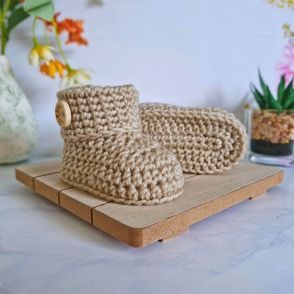 Knitted beige booties on a wooden stand with a blurred floral background