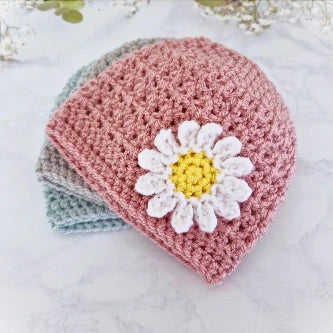 Handmade crochet baby beanies in pale rose, grey, and blue with a white and yellow daisy applique