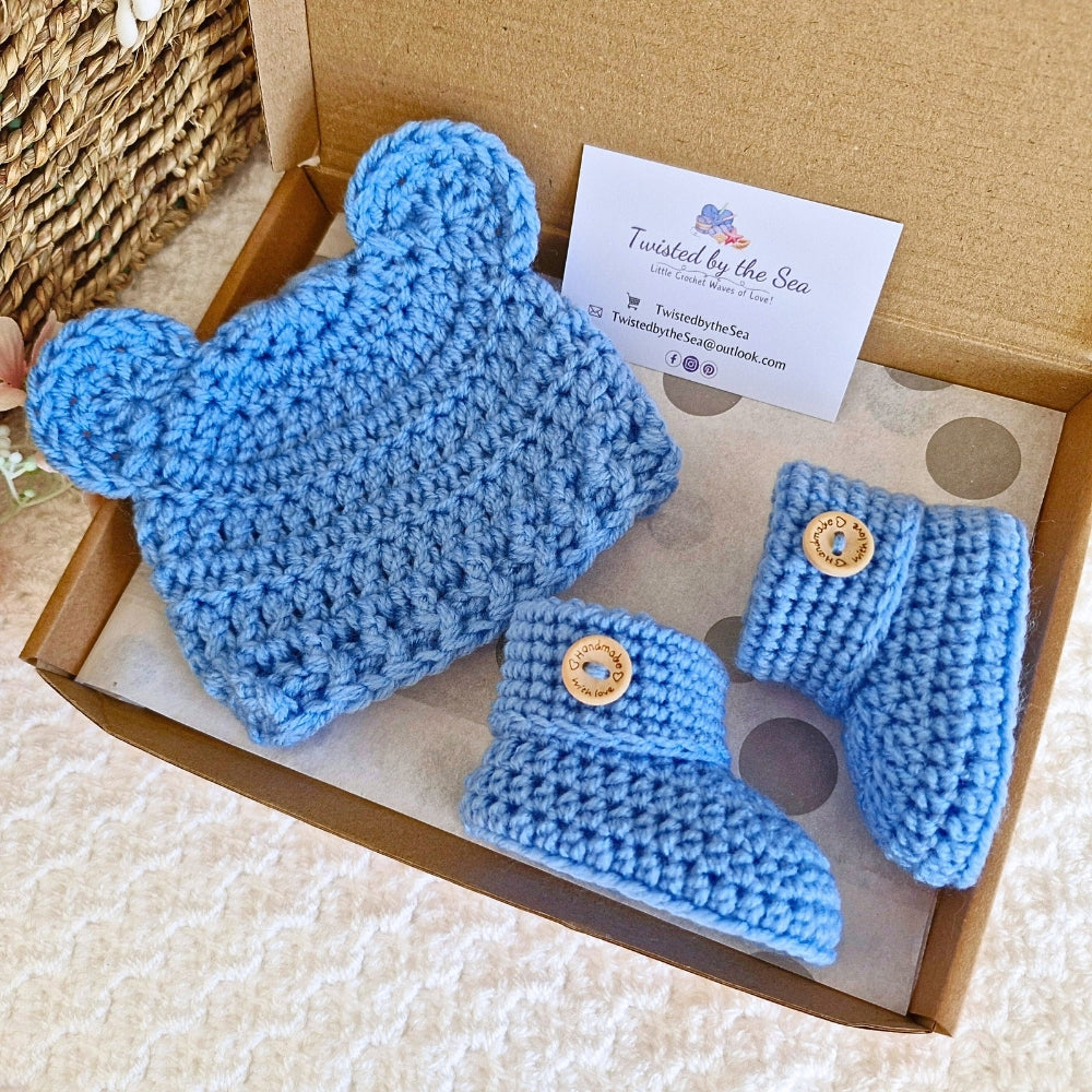 A matching baby blue crochet hat with teddy bear ears and a pair of seamless baby booties on a neutral background.