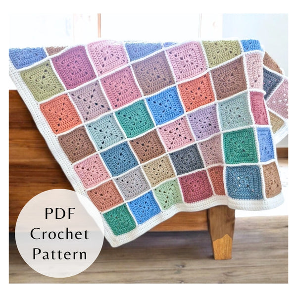 Multi-color crochet baby blanket made of 81 small squares with a white border. Stash busting PDF pattern by Twisted by the Sea.