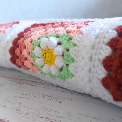 Close-up of a crocheted item with floral patterns on a wooden surface