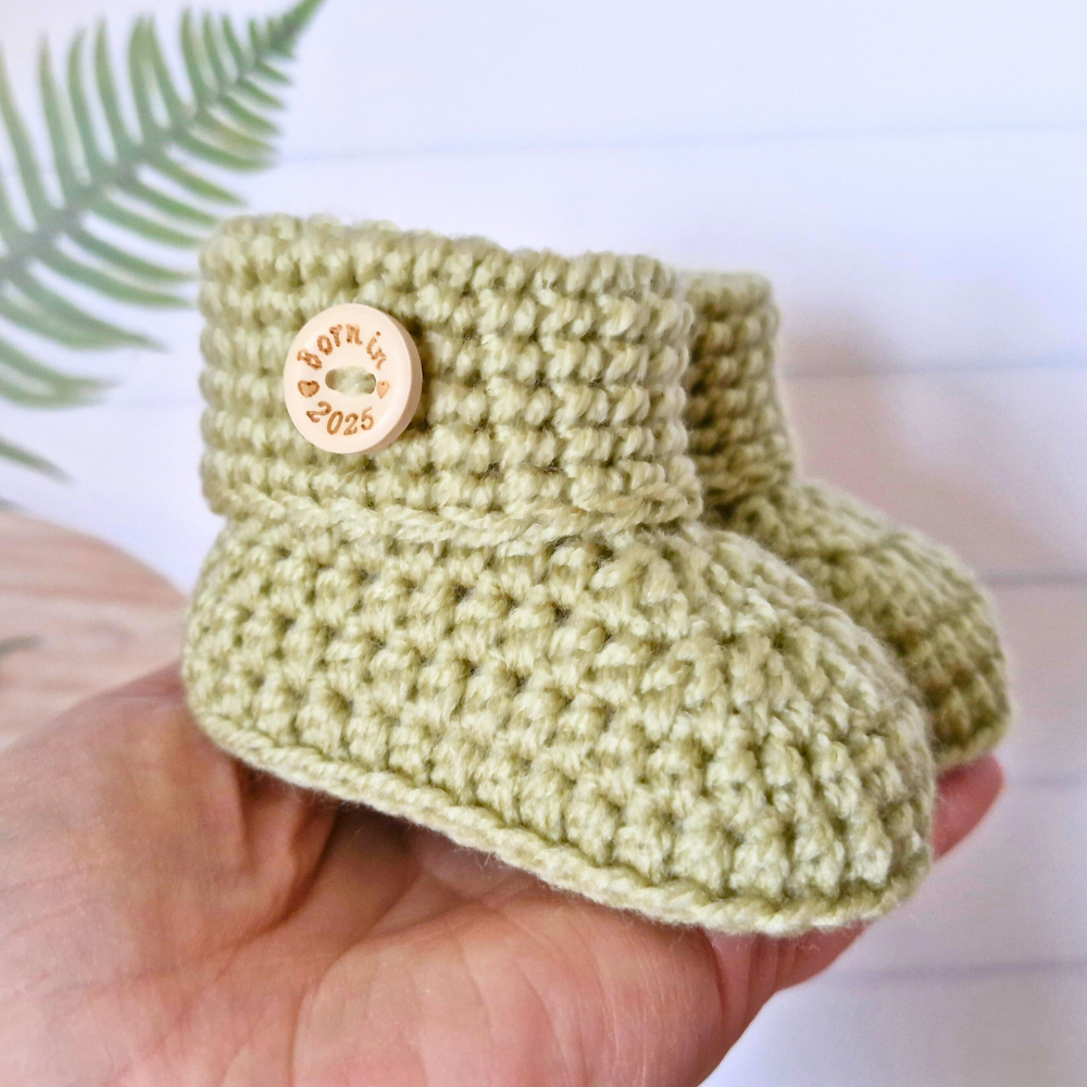 Handmade ‘Born in 2026’ Crochet Baby Booties – Handmade Newborn Gift or Pregnancy Reveal – Baby Booties crafted in soft acrylic yarn and available in multiple colours by Twisted by the Sea.