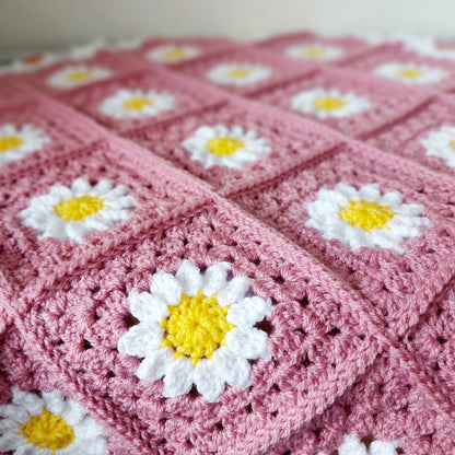 Pink crocheted blanket with daisy flower patterns