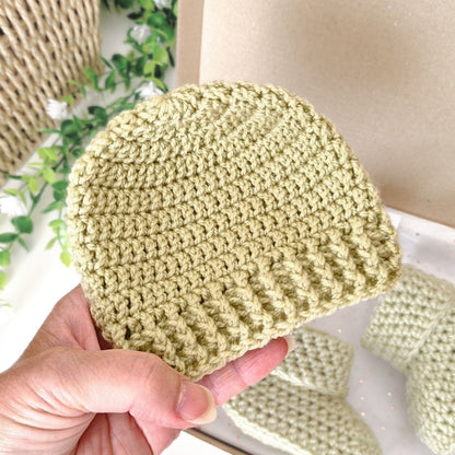 Hand holding a light mushy peas green crochet beanie 