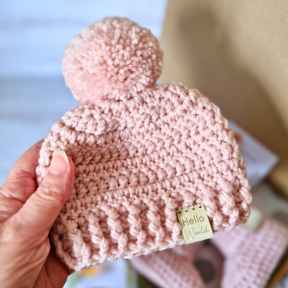 Handmade Hello World Chunky Crochet Pom-Pom Baby Hat – Handmade Winter Beanie – Pom Pom Hat crafted in soft acrylic yarn and available in multiple colours by Twisted by the Sea.