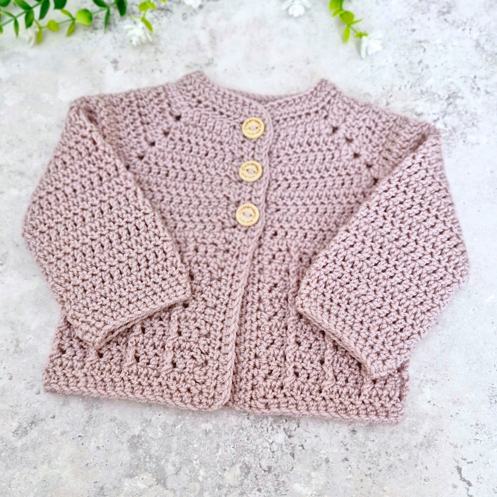 Neutral mushroom crochet baby cardigan with yellow buttons on a light gray background