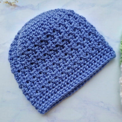 Blue crocheted beanie on a light marble background
