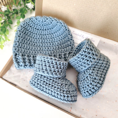 Blue crochet baby hat and booties on an open box