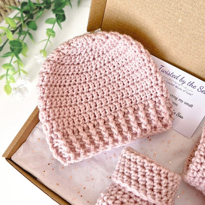 Pink crocheted baby hat and booties in a box 