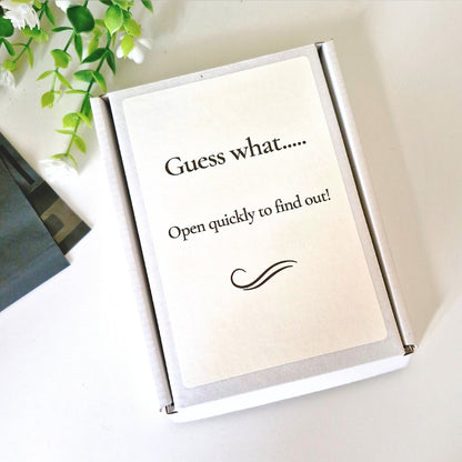 White box with text 'Guess what..... Open quickly to find out!' on a light background