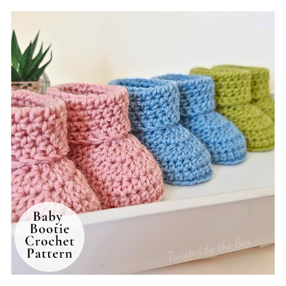 Three pairs of crocheted baby booties in pink, blue, and green on a white surface.