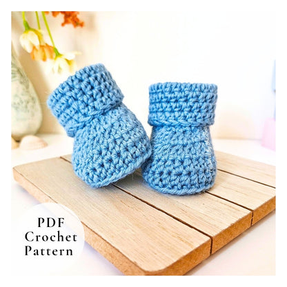 Pair of blue crochet baby booties on a wooden surface with 'PDF Crochet Pattern' text.