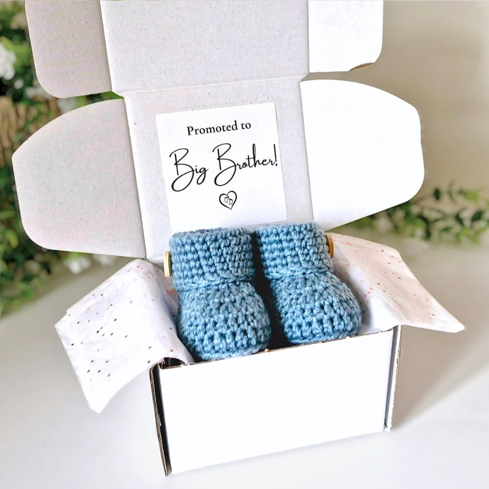 Blue baby booties in a box with a 'Promoted to Big Brother!' card.