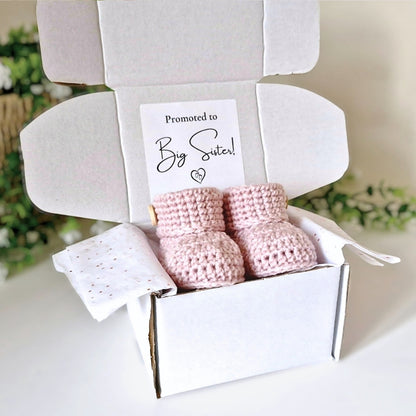 Pink baby booties and blanket in a box with 'Promoted to Big Sister!' card.