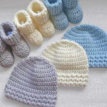 Collection of crocheted baby hats and booties in various colors on a light background