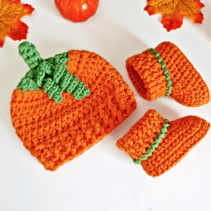 Handmade orange crochet baby pumpkin hat with a green stalk and matching pumpkin orange booties on a white background - Twisted by the Sea