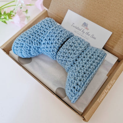 A pair of blue crochet baby booties lying in a box