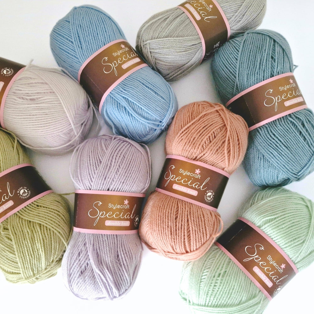 Eight skeins of yarn in soft pastel colors arranged on a white background, each wrapped with a brown paper label reading 'Stylecraft Special DK'.