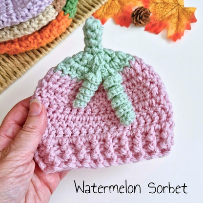 Hand holding a pink and green crocheted watermelon sorbet summerween baby hat
