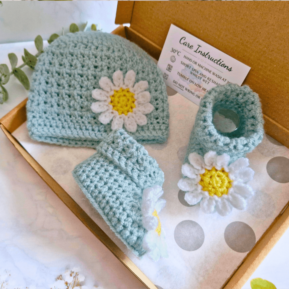 ​Handcrafted duck egg blue crochet baby set featuring a daisy beanie hat and matching booties on a gift box - Twisted by the Sea
