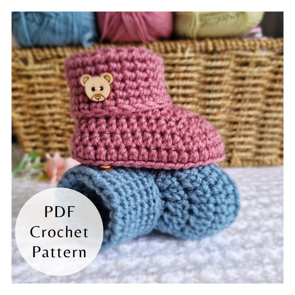 Handmade crochet baby booties with a folded cuff and wooden button detail. Three-size PDF pattern by Twisted by the Sea.