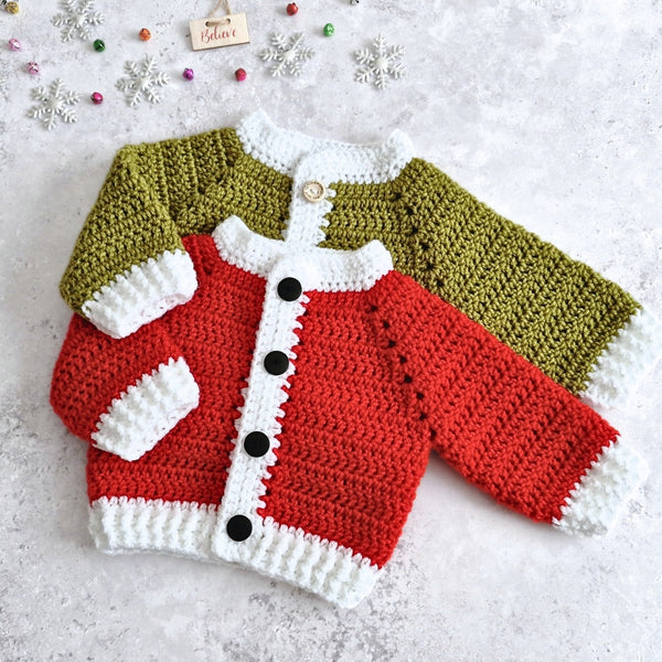 Two crocheted baby cardigans laid flat on a light textured surface, featuring a red and white cardigan wth black buttons, and a mistletoe green and white trim with wooden buttons. Small decorative snowflakes and beads are scattered around it.
