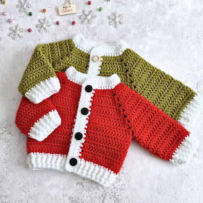 Two crocheted baby cardigans laid flat on a light textured surface, featuring a red and white cardigan wth black buttons, and a mistletoe green and white trim with wooden buttons. Small decorative snowflakes and beads are scattered around it.